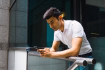 Homem de negócios adulto jovem usando telefone no escritório moderno — Fotografia de Stock