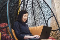 Jovem mulher asiática usando laptop no escritório moderno criativo — Fotografia de Stock