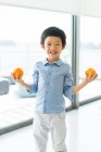 Süße kleine asiatische Junge mit orangen Früchten — Stockfoto
