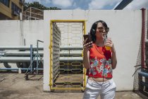 Азиатка в наушниках и солнцезащитных очках у стены — стоковое фото