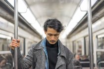 Молодий привабливий випадковий азіатський чоловік в громадському транспорті — стокове фото