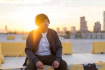 Young Asian millennial enjoying the sunset in headphones — Stock Photo