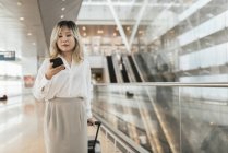 Joven exitosa mujer de negocios con smartphone en el aeropuerto - foto de stock