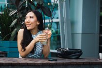 Junge asiatische Frau trinkt im Café — Stockfoto