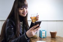 Jovem mulher em um café olhando para seu smartphone — Fotografia de Stock