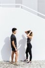 Happy asian sporty couple standing by wall — Stock Photo