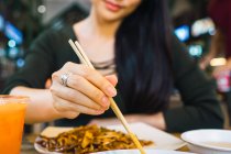 Joven asiático mujer comer comida con palillos - foto de stock
