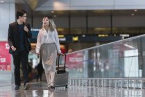 Young asian couple of businesspeople walking in airport — Stock Photo
