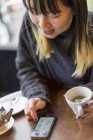 Joven atractivo casual asiático mujer usando smartphone en café - foto de stock
