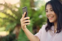 Feliz asiático mujer tomando selfie en parque - foto de stock