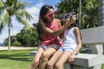 Mother and daughter wearing funny glasses on bench — Stock Photo
