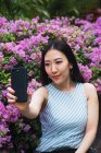 Joven asiático mujer tomando selfie con flores - foto de stock