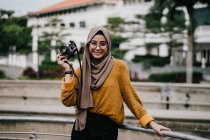 Junge asiatische muslimische Frau im Hidschab hält Kamera — Stockfoto