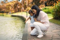 Cute asian mother and daughter beside pool in park — Stock Photo