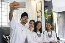 Giovane famiglia asiatica che celebra Hari Raya insieme a casa e scattare selfie — Foto stock