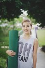 Junge asiatische Frau hält Trainingsmatte — Stockfoto
