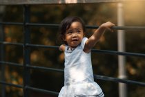 Piccolo carino asiatico ragazza accanto recinto a parco — Foto stock