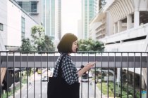 Молодая красивая азиатская девушка в повседневной одежде с помощью смартфона на улицах города — стоковое фото