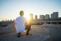 Rear view of young asian man hunker down at sunset — Stock Photo