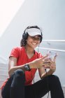 Giovane asiatica donna sportiva utilizzando cuffie e smart — Foto stock