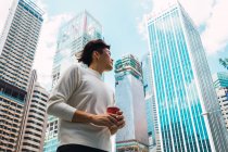 Young asian man in city street with coffee — Stock Photo