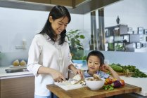 Щаслива молода азіатська сім'я готує разом на кухні — стокове фото