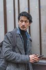 Молодой привлекательный случайный азиатский мужчина с помощью смартфона — стоковое фото