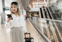 Jovem empresária bem sucedida com smartphone no aeroporto — Fotografia de Stock