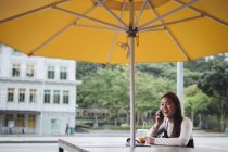 Chinês mulher de cabelo longo sentado à mesa — Fotografia de Stock
