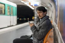 Jovem atraente casual asiático usando smartphone no metrô — Fotografia de Stock