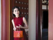 Donna cinese con borsetta rossa sorridente all'aperto — Foto stock