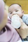 Asiatische muslimische Mutter füttert ihr Baby mit Milch. — Stockfoto