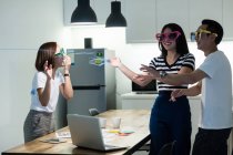 Giovani colleghi asiatici divertirsi con divertenti occhiali da sole in ufficio moderno — Foto stock