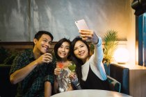 Giovani amici asiatici prendendo selfie in confortevole bar — Foto stock