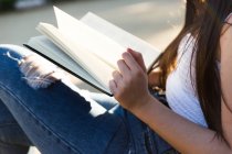 Cropped image of young Eurasian woman reading  book — Stock Photo