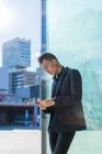 Молодий азіатський чоловік у костюмі, використовуючи смартфон на відкритому повітрі — стокове фото