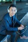 Jovem asiático homem com fone de ouvido e smartphone — Fotografia de Stock