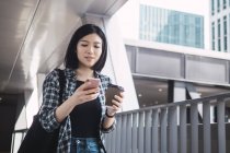 Jeune belle asiatique fille en casual vêtements en utilisant smartphone sur ville rues — Photo de stock