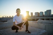 Joven asiático hombre hunker abajo contra sunset - foto de stock