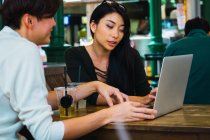 Young asian couple sharing laptop together in cafe — Stock Photo