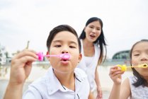 Happy asian family together, children making soap bubbles — Stock Photo
