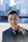 Retrato de sorrindo jovem asiático homem com fone de ouvido — Fotografia de Stock