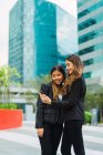 Jeunes femmes d'affaires asiatiques utilisant un smartphone sur la rue — Photo de stock
