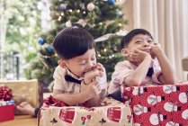 Happy asian family celebrating christmas together, boys with gifts near fir tree — Stock Photo