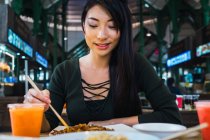 Junge Asiatin isst Essen mit Essstäbchen — Stockfoto