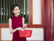 Mulher chinesa com bolsa vermelha sorrindo ao ar livre — Fotografia de Stock