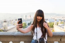 Donna eurasiatica che si fa un selfie con la fotocamera del telefono a Montjuic, Barcellona — Foto stock