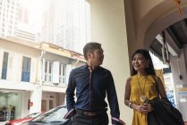 Happy young asian couple walking on the street — Stock Photo