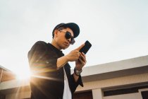 Крутий молодий азіатський чоловік використовує смартфон на відкритому повітрі — стокове фото