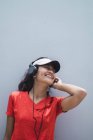 Jovem asiático desportivo mulher usando fones de ouvido contra cinza parede — Fotografia de Stock